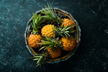 Wall Mural - Pineapples in a wooden box. Ripe baby pineapple. Tropical fruits. Top view. Free space for text.