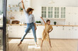 Leinwandbild Motiv Happy mother and little daughter moving to favorite music in modern kitchen together, young mom teaching adorable kid girl to dance, family engaged in funny activity at home, enjoying leisure time