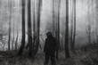 A mysterious spooky hooded figure with glowing eyes standing in a forest. With an artistic, blurred, textured edit.