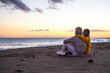 © Daniel - Portrait of couple of mature and old people enjoying summer at the beach looking to the sea smiling and having fun together with the sunset at the background. Two active seniors traveling outdoors..