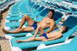 © Andrii - A young athletic man and his son are smiling happily and sunbathing on a sun lounger on a sunny day. Happy vacation vacation. Summer holidays and tourism.