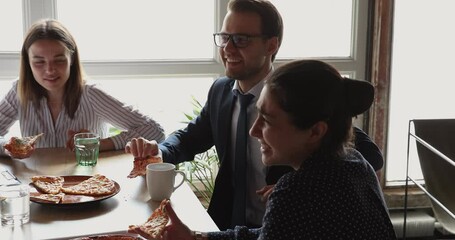 Wall Mural - Multi racial office employees talking while eating pizza during lunch break at workplace. Indian and Caucasian colleagues company staff joking having good friendly conversation enjoy pause at workday