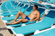 © Andrii - A young athletic man is smiling happily and sunbathing on a sun lounger on a sunny day. Happy vacation vacation. Summer holidays and tourism.