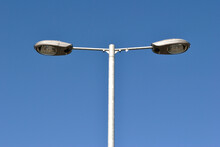 Isolated Steel Lighting Pole With Two Modern Lamps Against Blue Sky