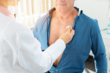 Wall Mural - Doctor checking lung function of male patient with stethoscope