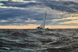 © Vladimir Drozdin - The lonely sailboat on the horizon in sea at sunset, the storm sky of different colors, big waves, sail regatta, cloudy weather, only main sail, sun beams