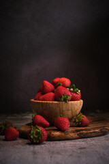 strawberries in a wooden bowl on a gray background