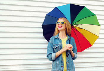 Wall Mural - Portrait of happy smiling young woman with colorful umbrella on a white background