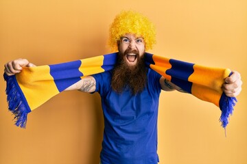 Sticker - Redhead man with long beard football hooligan cheering game wearing funny wig celebrating crazy and amazed for success with open eyes screaming excited.