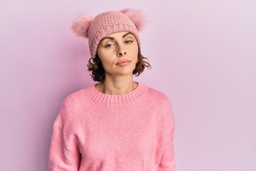 Sticker - Young brunette woman wearing cute wool cap relaxed with serious expression on face. simple and natural looking at the camera.