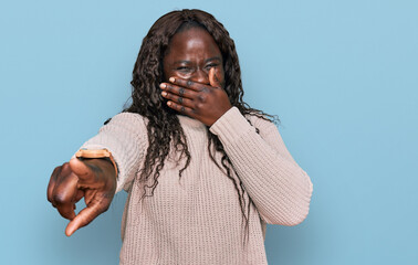 Poster - Young african woman wearing wool winter sweater laughing at you, pointing finger to the camera with hand over mouth, shame expression