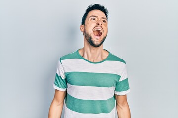 Poster - Young hispanic man wearing casual clothes angry and mad screaming frustrated and furious, shouting with anger. rage and aggressive concept.