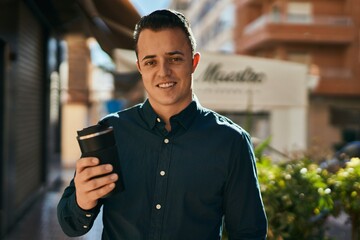 Young hispanic man smiling happy drinking coffee at the city.