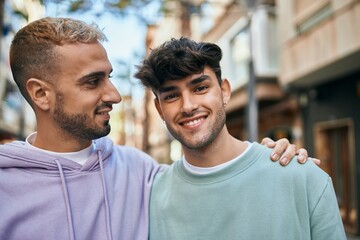 Young gay couple smiling happy and hugging at the city.