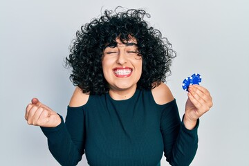 Sticker - Young middle east woman playing poker holding casino chips screaming proud, celebrating victory and success very excited with raised arm