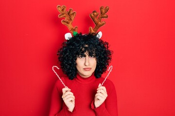 Sticker - Young middle east woman wearing cute christmas reindeer horns skeptic and nervous, frowning upset because of problem. negative person.