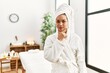 © Krakenimages.com - Young brunette woman wearing towel and bathrobe standing at beauty center looking confident at the camera with smile with crossed arms and hand raised on chin. thinking positive.