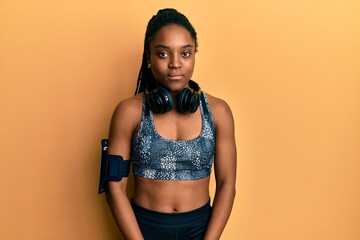 Wall Mural - African american woman with braided hair wearing sportswear and arm band relaxed with serious expression on face. simple and natural looking at the camera.