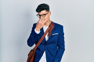 Sticker - Young hispanic man wearing business clothes smelling something stinky and disgusting, intolerable smell, holding breath with fingers on nose. bad smell