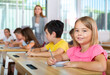 © JackF - Kids studying in classroom. Girl sitting at desk and looking in camera.