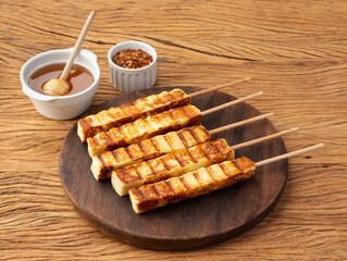 Grilled Rennet or Coalho cheese on a wooden board with sugar syrup and pepper