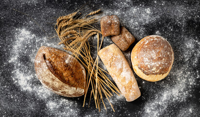 Aufkleber - Bakery background. Freshly baked crispy bread and buns with ears of wheat top view