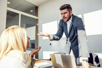 The CEO is standing in the office arguing with his employee. He takes an unpleasant attitude and raises his voice at her. Business meeting, disagreement