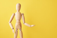 Wooden Doll With Gesture On Yellow Background. Mannequin Shows Gesture. Figure Of Wooden Human With Copy Space