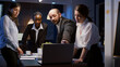 © DC Studio - Diverse teamwork checking management presentation on laptop computer brainstorming company ideas. Multi ethnic businesspeople lean on conference table in office meeting room late at night