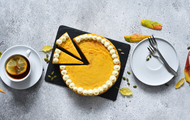 Wall Mural - Delicate cheesecake with pumpkin on a wooden board on a concrete background.