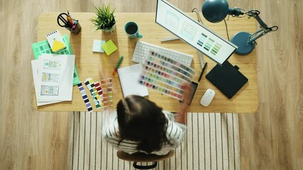 Top view time lapse of young woman designing smartphone app interface working with computer looking at color palettes sitting at desk in office