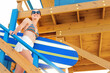 Scenic portrait young adult beautiful slim sporty woman with surfboard go downstairs from vintage wooden safety rescue lifeguard baywatch ocean beach tower bright sunny day. Travel vacation concept