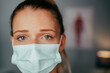 Caucasian female nurse standing in doctors office wearing surgical mask
