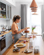 © Syda Productions - culinary, baking and cooking food concept - happy smiling young woman making layer cake on kitchen at home