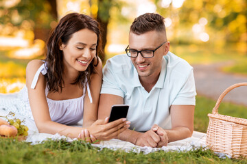 Poster - leisure and people concept - happy couple with smartphone having picnic at summer park