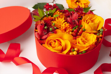 Wall Mural - festive composition with beautiful flowers and berries in red round box on white background. flat la