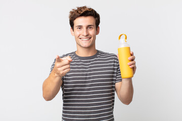 young handsome man pointing at camera choosing you and holding a coffee thermos