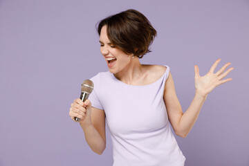 Poster - Young fun brunette expressive caucasian happy woman 20s with bob haircut wear white t-shirt singing song in microphone spread hand at karsoke club isolated on pastel purple background studio portrait.