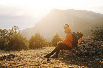 Wall Mural - Young traveler with backpack resting while walking at sunset.