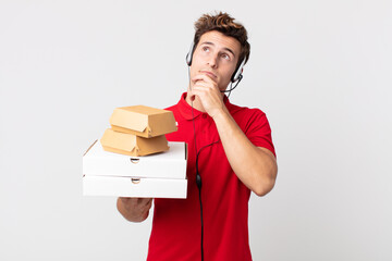 Wall Mural - young handsome man thinking, feeling doubtful and confused. take away fast food concept