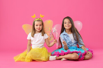 Sticker - Cute little girls in fairy costumes with wings and magic wands on pink background