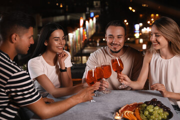 Wall Mural - Friends with glasses of cocktails spending time together on roof cafe terrace at night