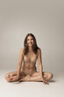 © master1305 - Young adorable woman in lingerie sitting on floor isolated over gray studio background. Natural beauty concept.
