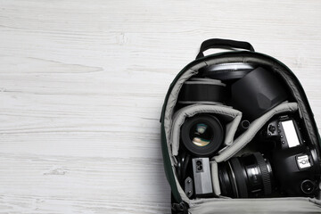 Wall Mural - professional photography equipment in backpack on white wooden table, top view. space for text