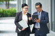 © DragonImages - Senior business couple discussing information on tablet computer when having meeting outdoors