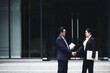 © DragonImages - Smiling senior business people meeting outdoors and shaking hands before having important conversation