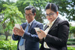 © DragonImages - Positive senior business people in glasses standing in park and texting colleagues trying to manager work in office online