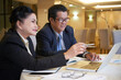 © DragonImages - Senior business people sitting at restaurant table and pointing at laptop screen when watching presentation of new project