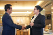 © DragonImages - Smiling senior entrepreneur and his female business partner shaking hands and looking at each other