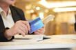 © DragonImages - Close-up image of female restaurant owner paying with credit card when ordering staff for kitchen and bar online